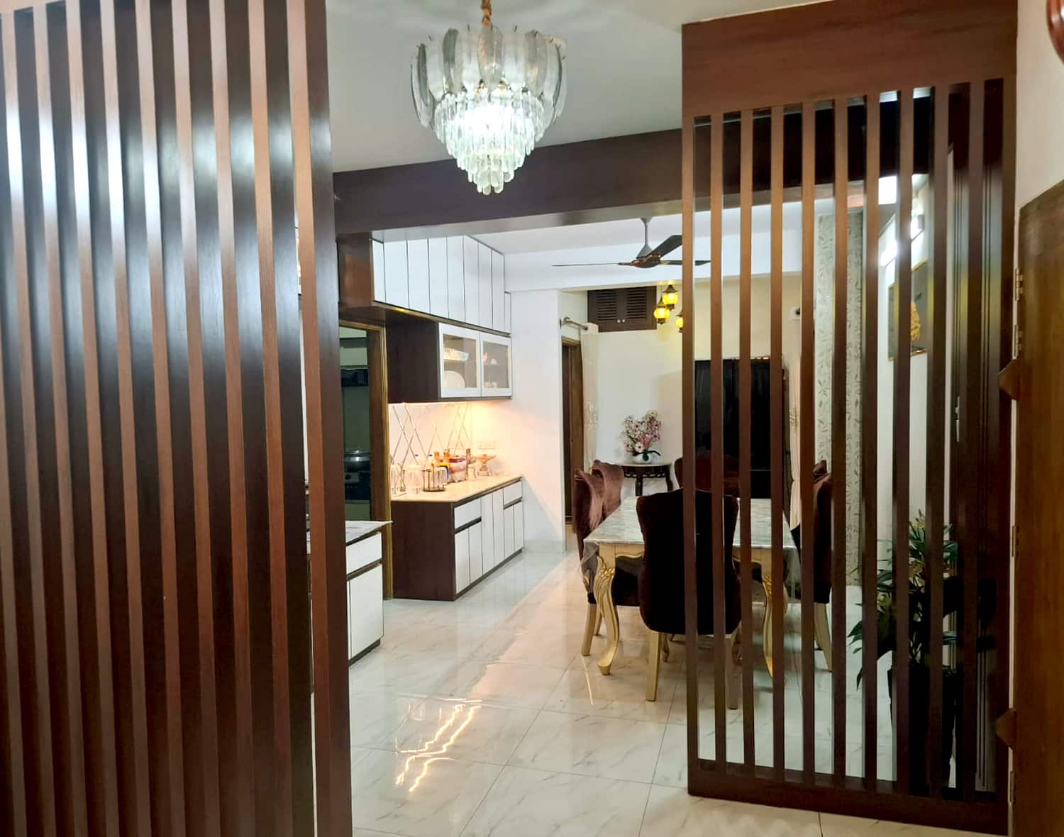 Entry foyer view with vertical wooden louver partition framing living and kitchen circulation - residence interior design for Mr. Khan, Bashundhara, Dhaka