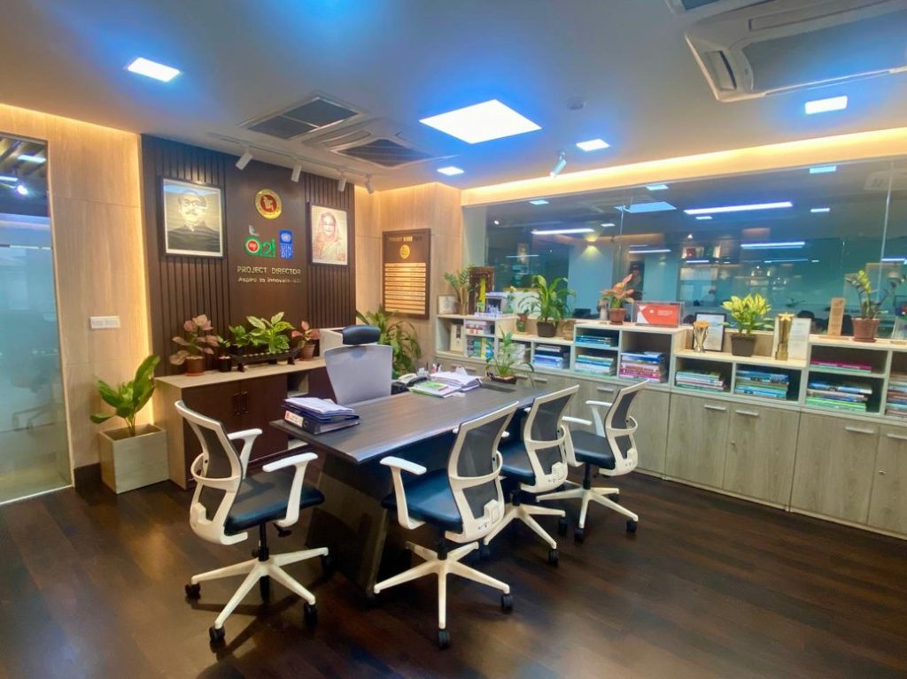 a2i office meeting area with branded wall, planted shelving and custom conference table, Dhaka