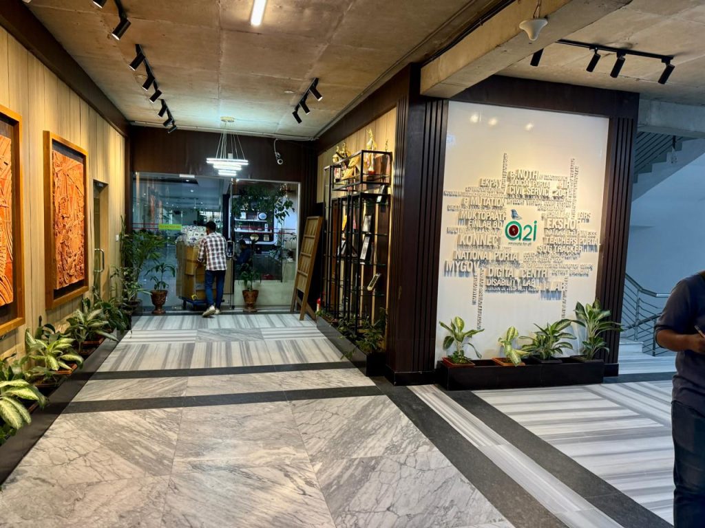 Corridor and reception lobby with branded a2i feature wall, wooden panelling and plants, office interior, Dhaka