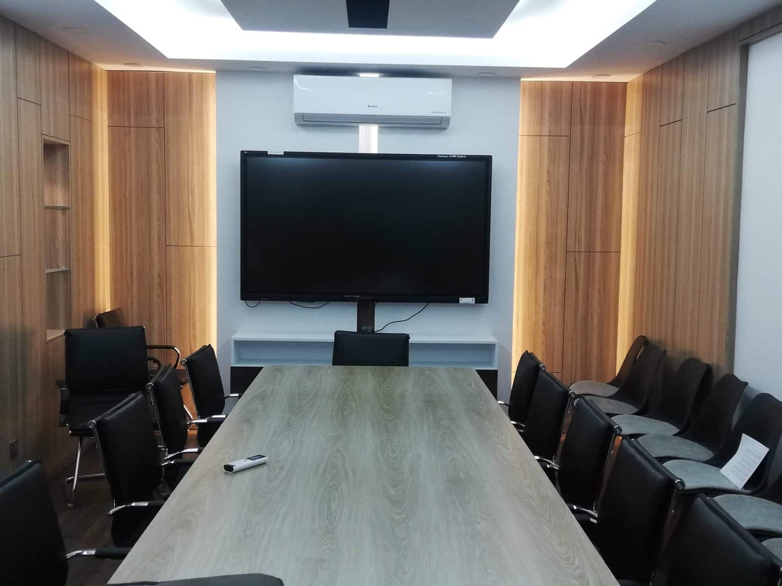 Conference room with wall-mounted display screen, wood-paneled walls and long meeting table, K4DM, Planning Ministry, Dhaka