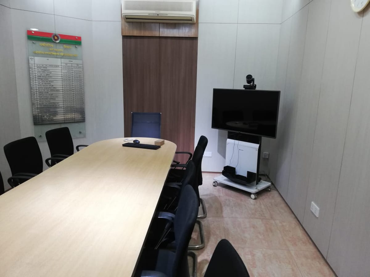 Small conference room with video conferencing display, oval table and seating in K4DM conference room interior, Planning Ministry, Dhaka