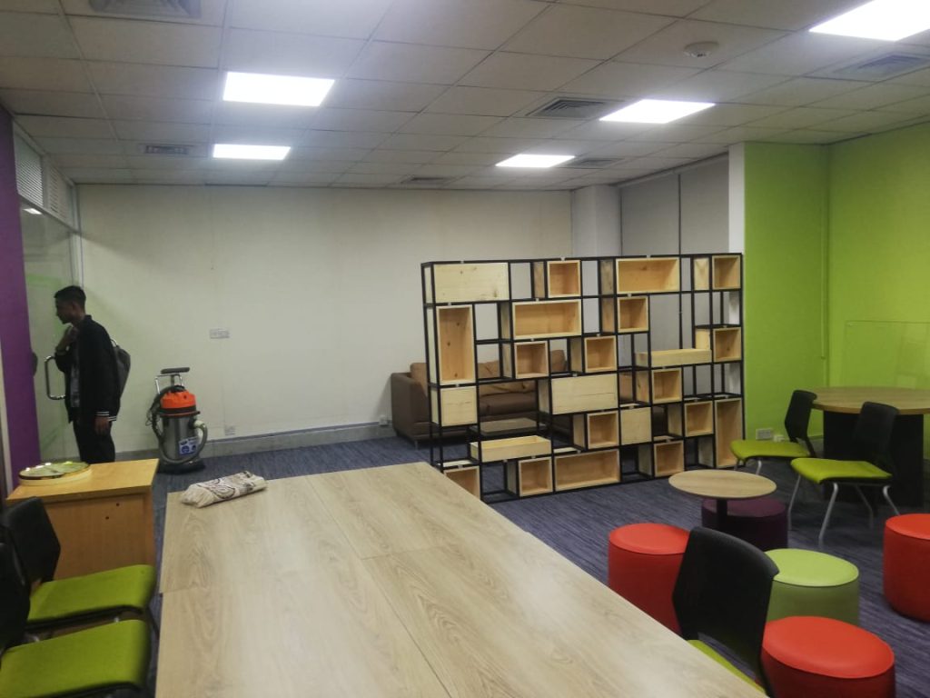 Open office design layout with long tables, shelves and soft seating in a 600 sft adaptable workspace.