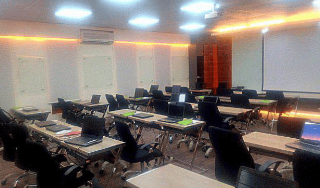 Training room with projector screen, ergonomic chairs, and wall panel finishes.