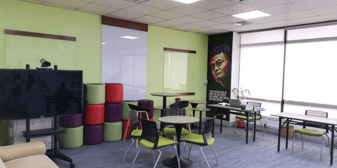 Open office design workspace with TV wall, tables and stools for team discussion.