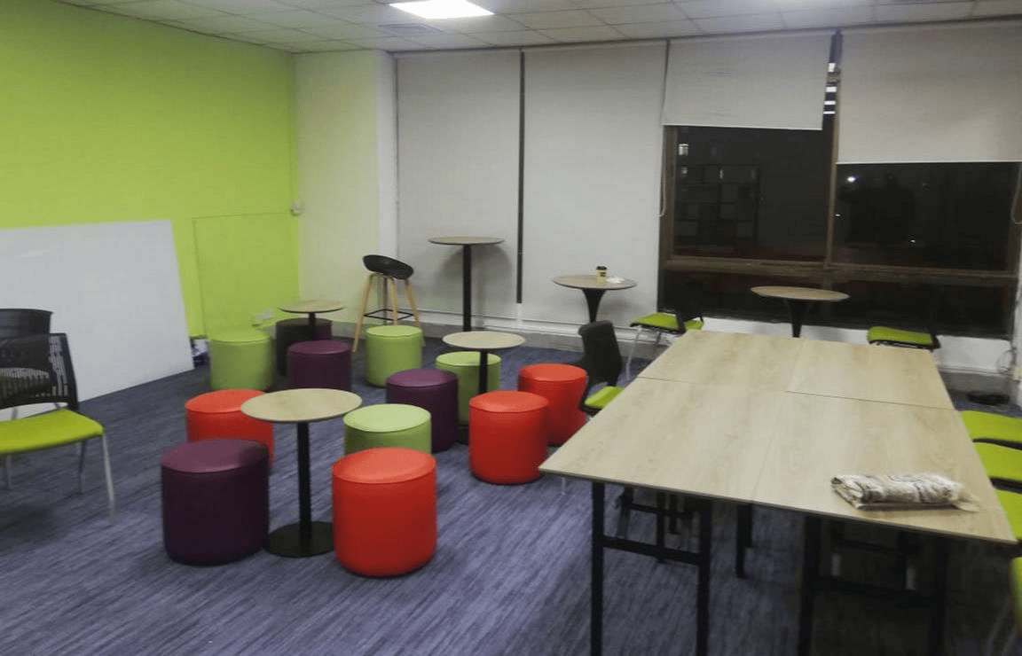 Adaptable workspace with folding table setup and colorful stools for group workshops. - UNCDF FinLab open office design, IDB Bhaban, Dhaka