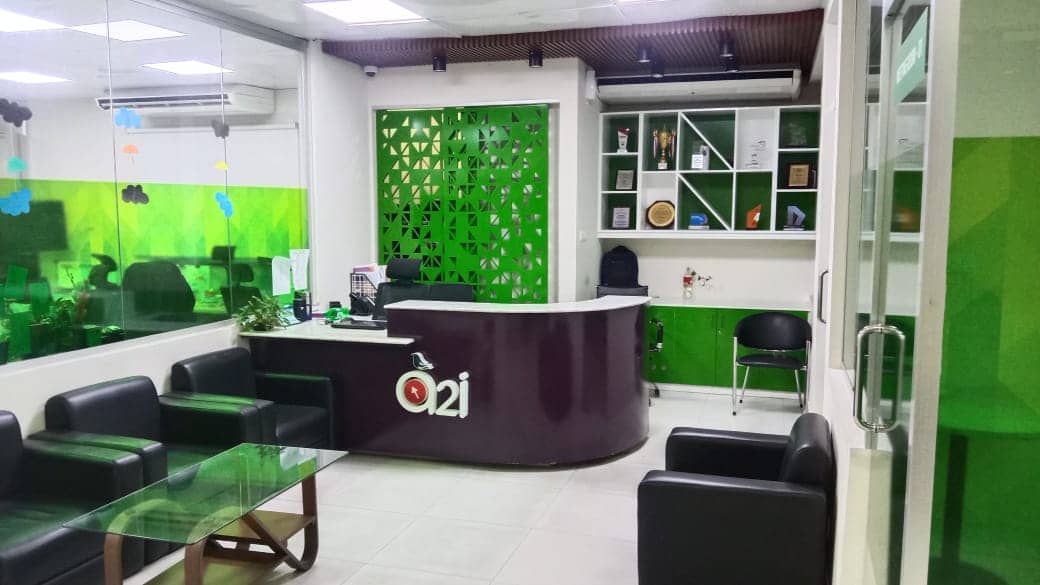 Reception desk with A2i branding and green geometric partition wall, A2i Paribahan Pool office interior design in Segunbagicha, Dhaka