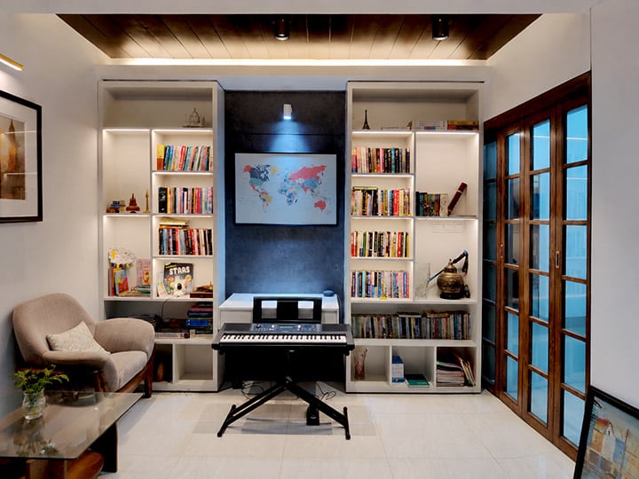 Home office with built-in bookshelves, world map wall art, keyboard piano and wooden-frame glass folding door - residence interior design in Rampura, Dhaka
