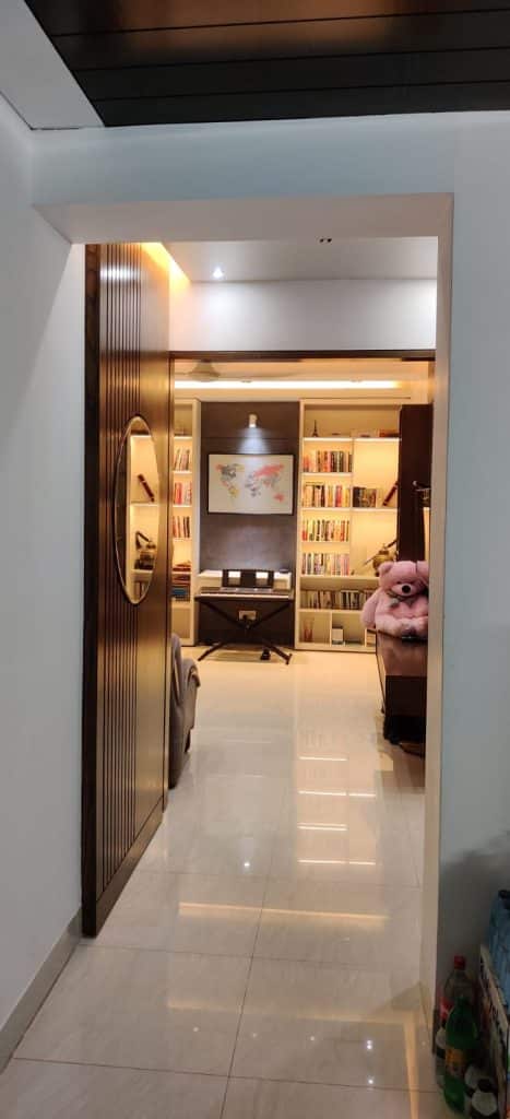 Hallway view into open home office and reading corner with bookshelves and world map artwork - residence interior design in Rampura, Dhaka