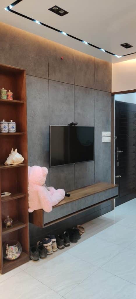 Entrance foyer with grey stone-clad TV media wall, wooden display shelf, and built-in shoe storage - residence interior design in Rampura, Dhaka